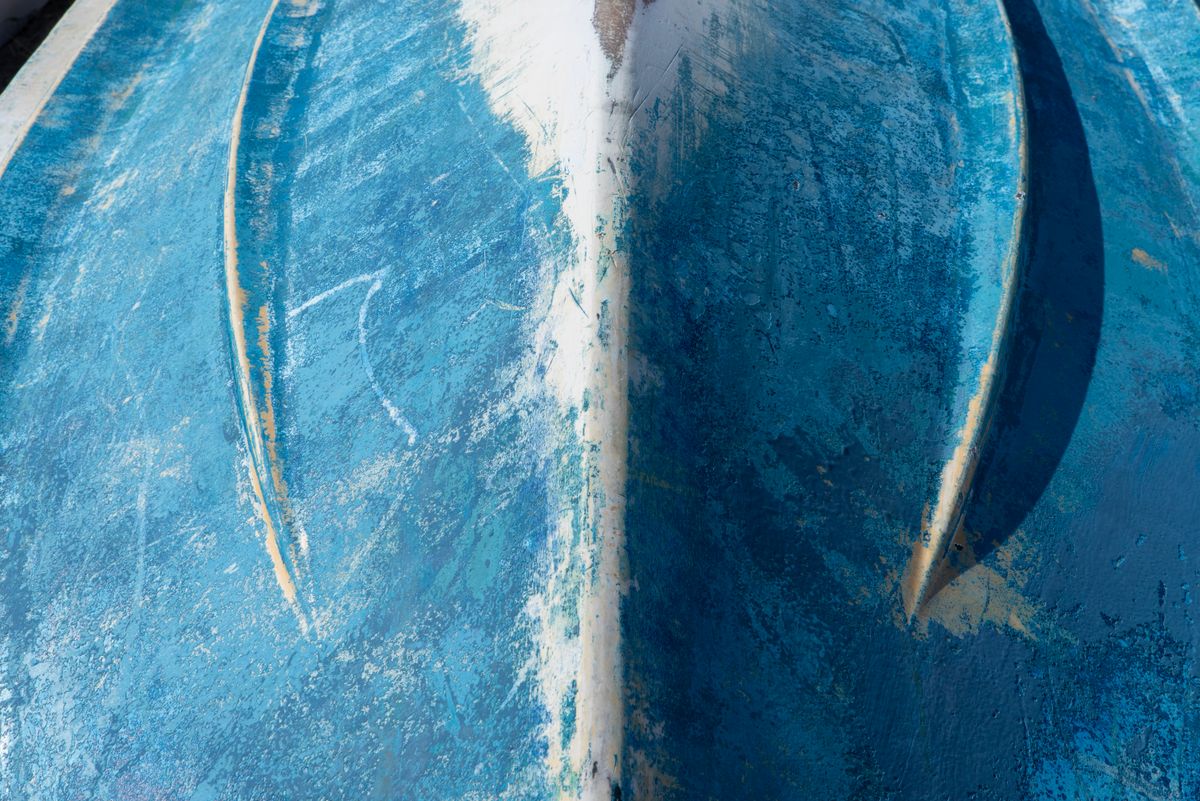Worn blue fiberglass boat hull showing oxidation and gel coat damage that needs repair
