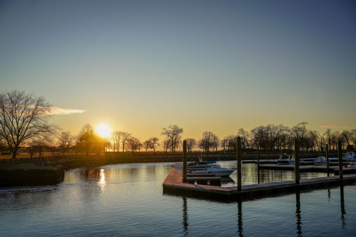 Boat dock at sunset with motorboats moored in calm marina